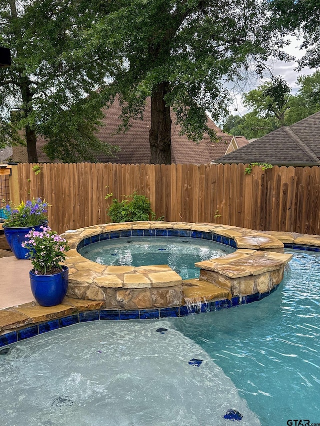 view of pool with an in-ground hot tub and fence
