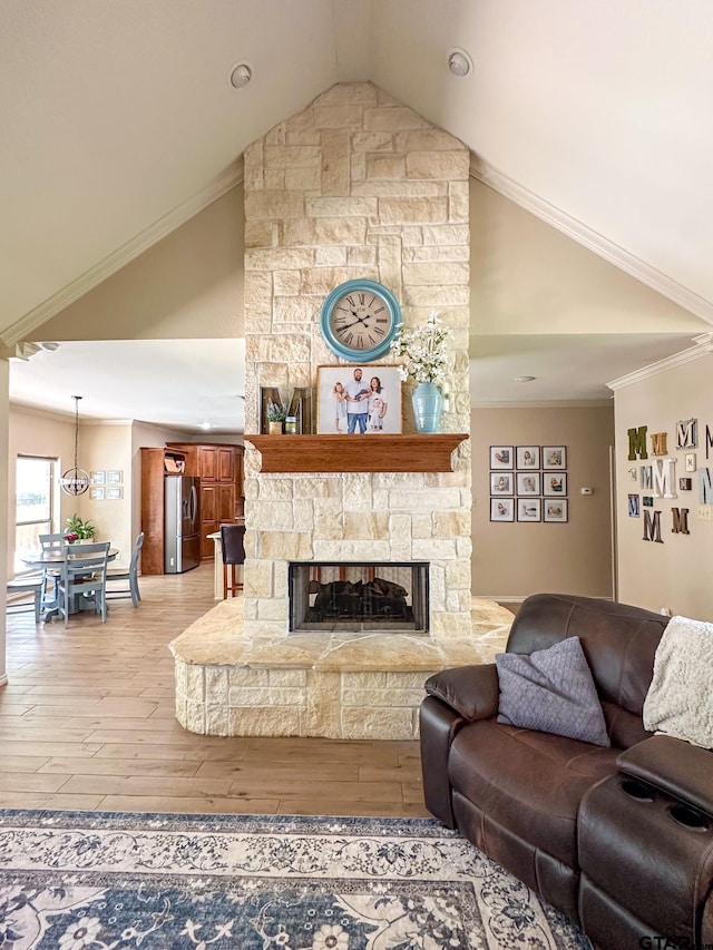 living area featuring ornamental molding, wood finished floors, a stone fireplace, baseboards, and high vaulted ceiling
