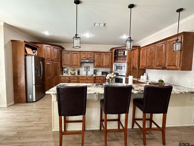 kitchen with appliances with stainless steel finishes, a peninsula, crown molding, decorative backsplash, and light stone counters