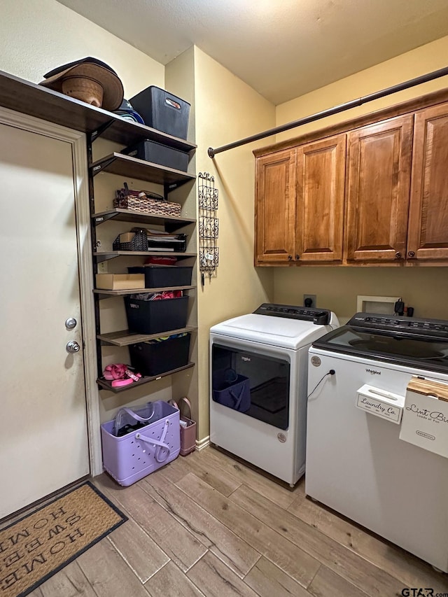 clothes washing area with cabinet space, washer and dryer, and light wood finished floors