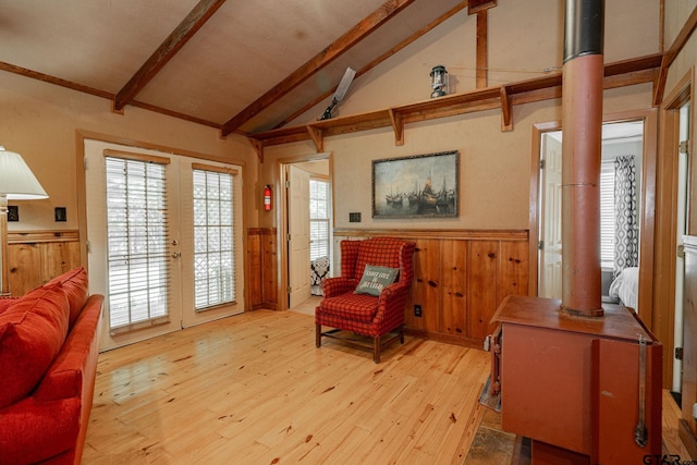 living area featuring french doors, lofted ceiling with beams, light hardwood / wood-style floors, and wood walls