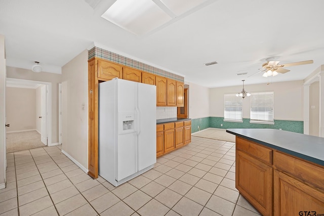 kitchen featuring ceiling fan with notable chandelier, white fridge with ice dispenser, and light tile patterned floors