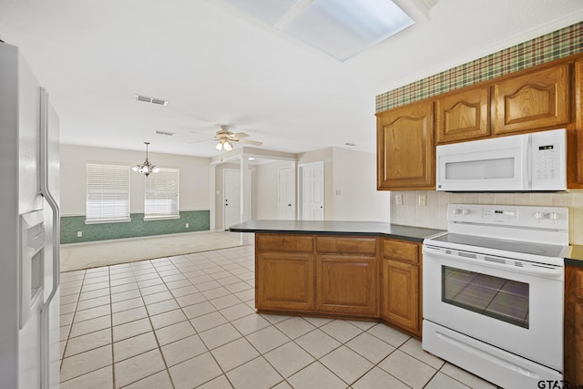 kitchen with brown cabinets, dark countertops, visible vents, open floor plan, and white appliances