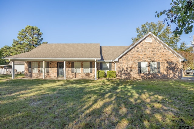 view of front of home with brick siding, roof with shingles, and a front yard