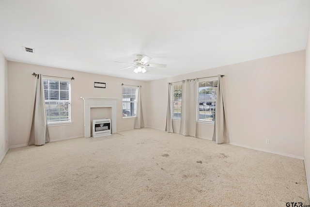 unfurnished living room with a wealth of natural light, light colored carpet, and heating unit