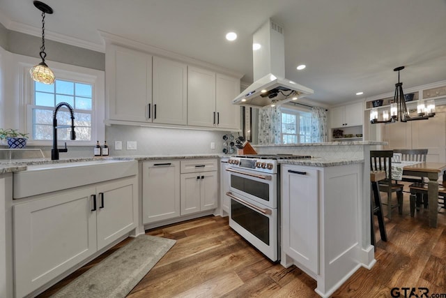 kitchen with range with two ovens, white cabinetry, hardwood / wood-style floors, and island range hood