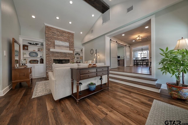 living room with built in features, high vaulted ceiling, a fireplace, dark hardwood / wood-style flooring, and a barn door