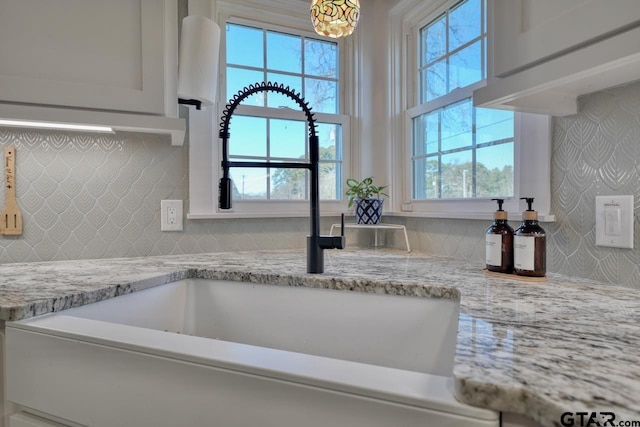 room details with sink, backsplash, and light stone countertops