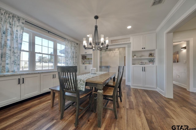 dining area featuring dark wood-type flooring, crown molding, built in shelves, and a notable chandelier