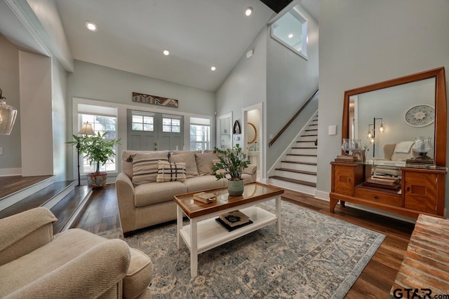 living room with dark hardwood / wood-style flooring, high vaulted ceiling, and a wealth of natural light