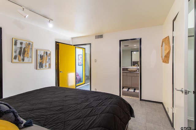 bedroom featuring ensuite bathroom, rail lighting, and sink