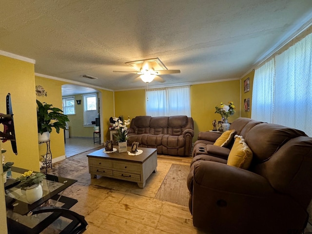 living room with ceiling fan, a textured ceiling, and crown molding