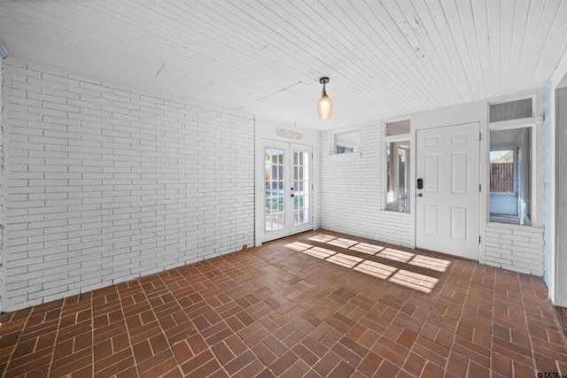 interior space featuring wooden ceiling, brick wall, and french doors