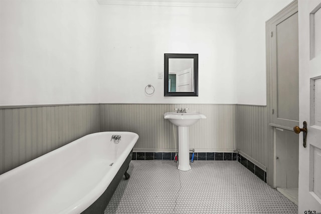 bathroom featuring tile patterned flooring, ornamental molding, and a bathing tub