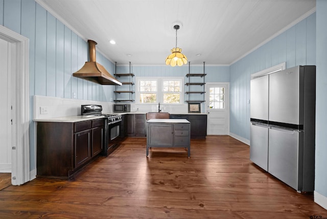 kitchen featuring dark hardwood / wood-style flooring, wall chimney exhaust hood, stainless steel appliances, crown molding, and decorative light fixtures