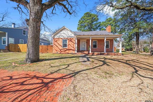 bungalow featuring a front yard, fence, brick siding, and a chimney