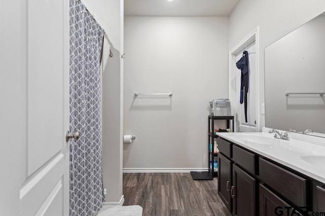 bathroom with double vanity, a sink, baseboards, and wood finished floors