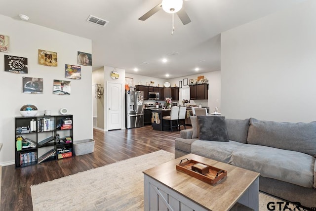 living room featuring baseboards, visible vents, dark wood finished floors, and a ceiling fan