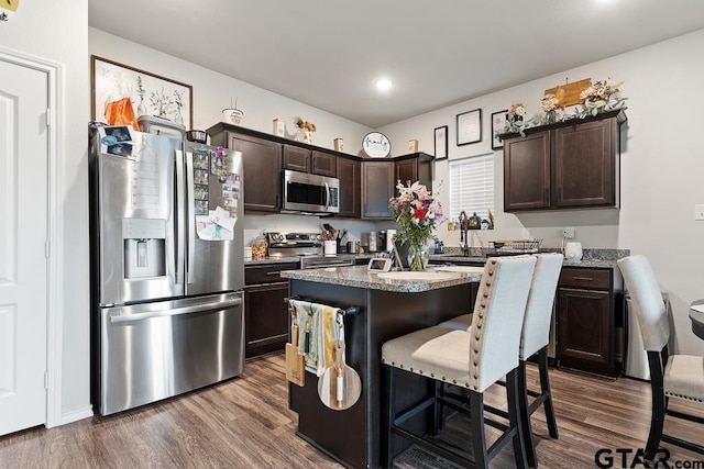 kitchen featuring stainless steel appliances, a breakfast bar area, a kitchen island, and dark brown cabinets