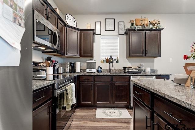 kitchen with dark brown cabinetry, light wood-style flooring, appliances with stainless steel finishes, and a sink