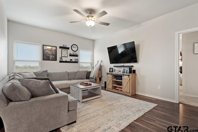 living area with baseboards, wood finished floors, a ceiling fan, and a healthy amount of sunlight