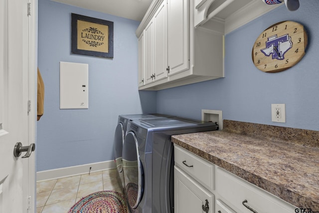 clothes washing area with washing machine and clothes dryer, light tile patterned flooring, and cabinets