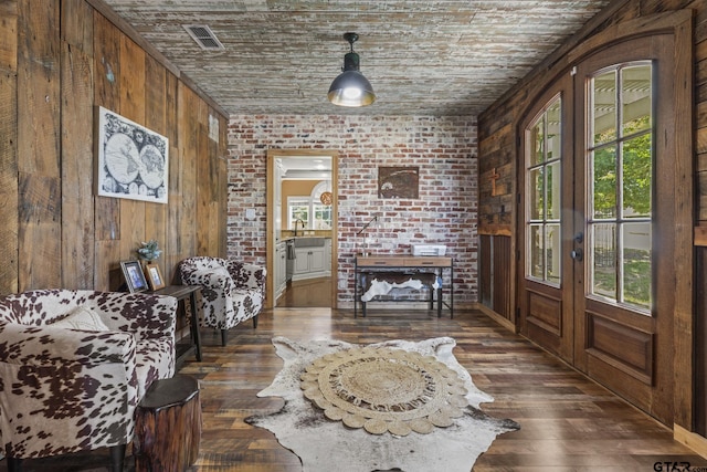 sitting room featuring a brick fireplace, brick wall, wood ceiling, dark hardwood / wood-style floors, and wood walls