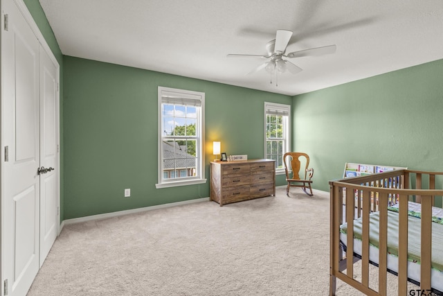 bedroom with a closet, ceiling fan, and light colored carpet