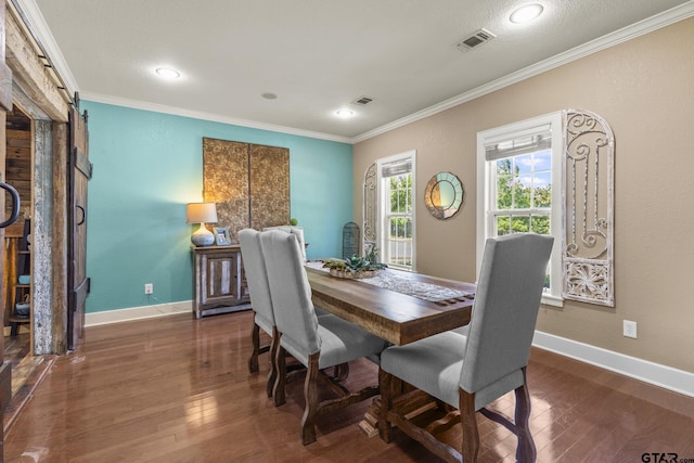 dining space featuring a barn door, dark hardwood / wood-style flooring, and crown molding