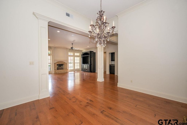 unfurnished living room with ornate columns, crown molding, ceiling fan with notable chandelier, and hardwood / wood-style floors