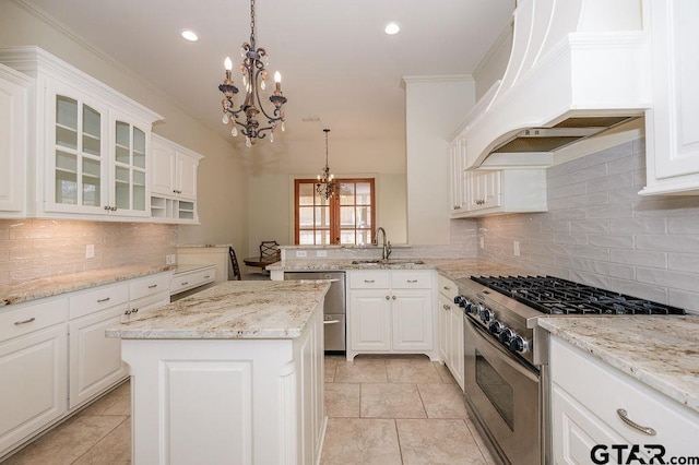 kitchen with pendant lighting, appliances with stainless steel finishes, premium range hood, white cabinets, and a kitchen island