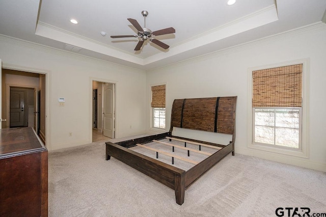 bedroom with light colored carpet, ornamental molding, and a tray ceiling