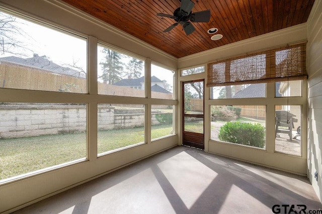 unfurnished sunroom featuring ceiling fan, plenty of natural light, and wooden ceiling