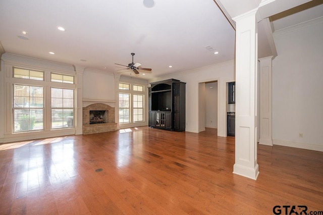 unfurnished living room featuring ornate columns, wood-type flooring, crown molding, and ceiling fan