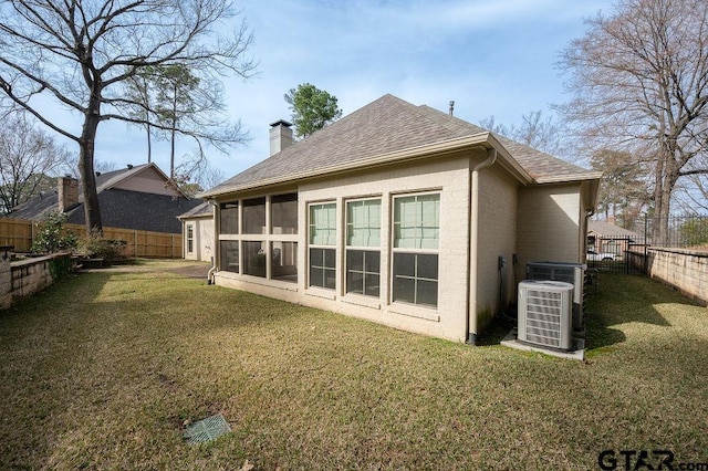 rear view of property featuring a yard, central AC unit, and a sunroom