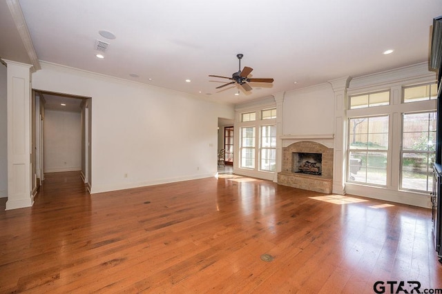 unfurnished living room featuring a healthy amount of sunlight, ornamental molding, and hardwood / wood-style floors