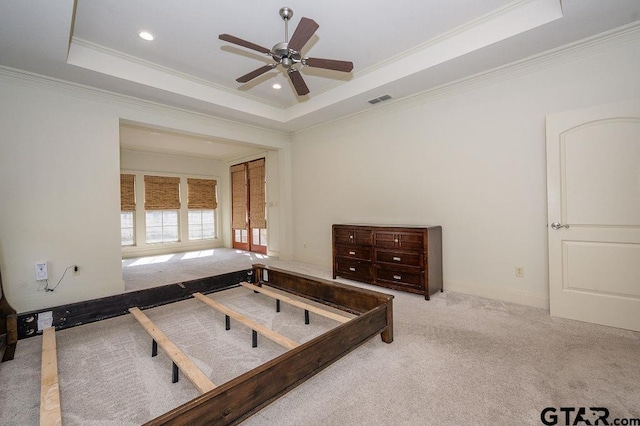 bedroom with crown molding, light colored carpet, and a raised ceiling