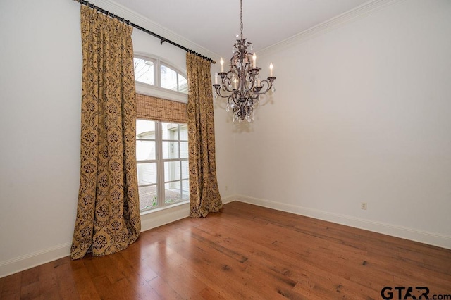 empty room with ornamental molding, a chandelier, and hardwood / wood-style floors