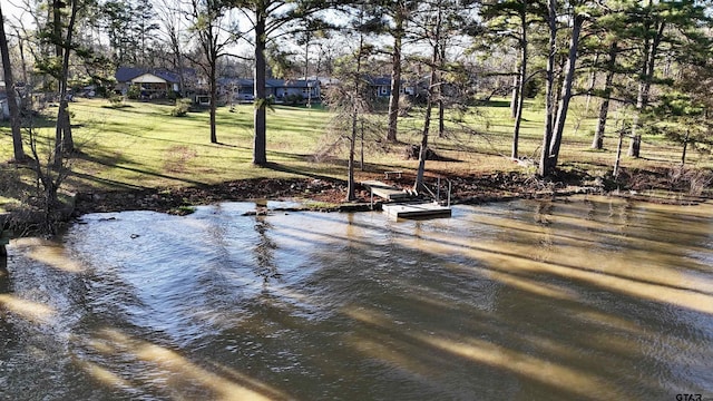 exterior space featuring a yard, a water view, and a boat dock