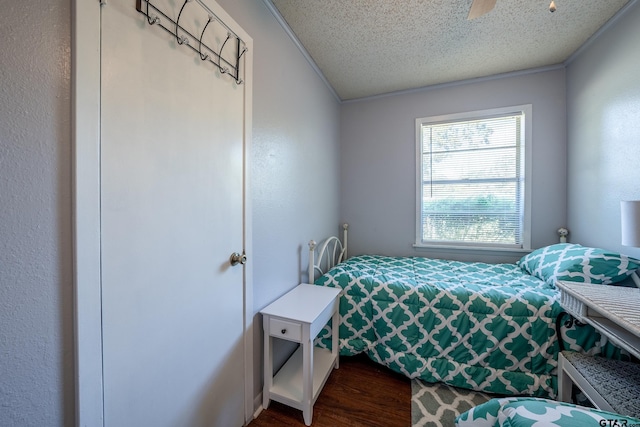 bedroom with ceiling fan, crown molding, dark hardwood / wood-style floors, and a textured ceiling