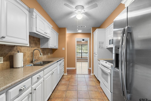 507 Hyde Park, Tyler, TX 75701 - kitchen with white appliances, a ceiling fan, a textured ceiling, tasteful backsplash, and white cabinets