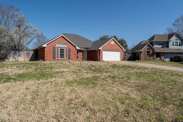 view of front facade with driveway, brick siding, a front yard, and fence