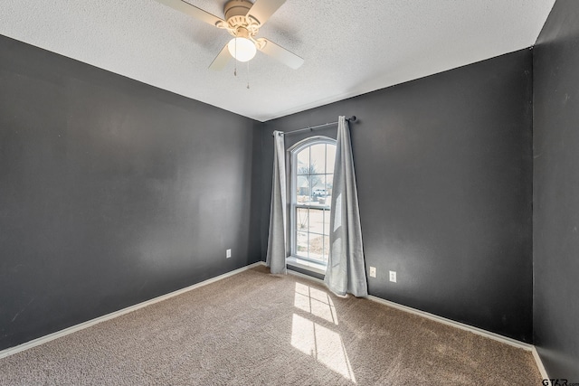 carpeted spare room with a textured ceiling, a ceiling fan, and baseboards