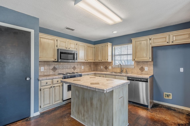 kitchen with tile countertops, stainless steel appliances, baseboards, and a sink