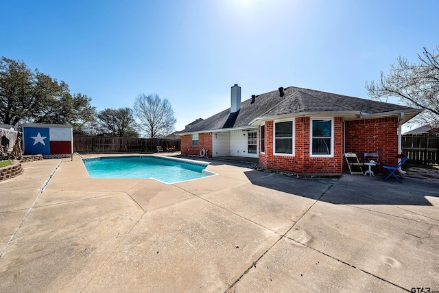 view of swimming pool with a patio, an outbuilding, a fenced in pool, a fenced backyard, and a storage unit