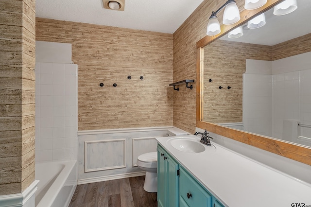 full bathroom with a tub, toilet, vanity, wood finished floors, and a textured ceiling