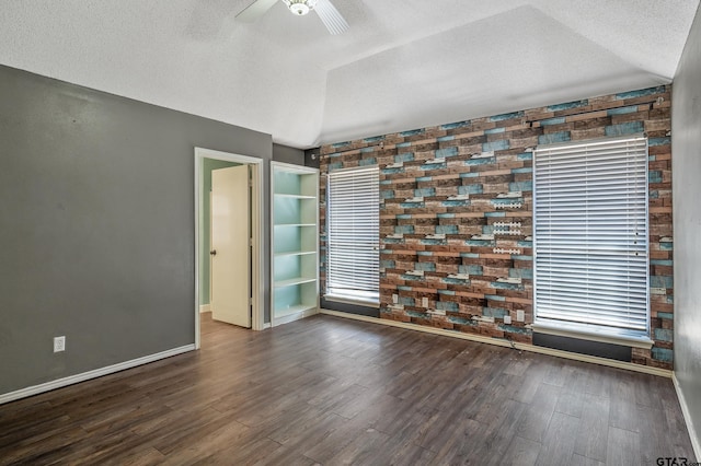 unfurnished room featuring a textured ceiling, lofted ceiling, a ceiling fan, and wood finished floors