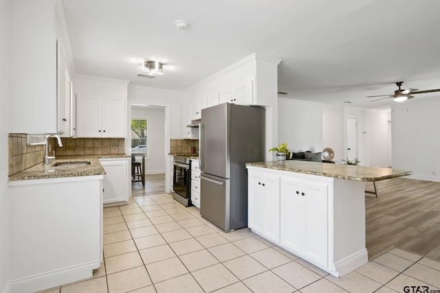 kitchen featuring a peninsula, a sink, white cabinets, and stainless steel appliances