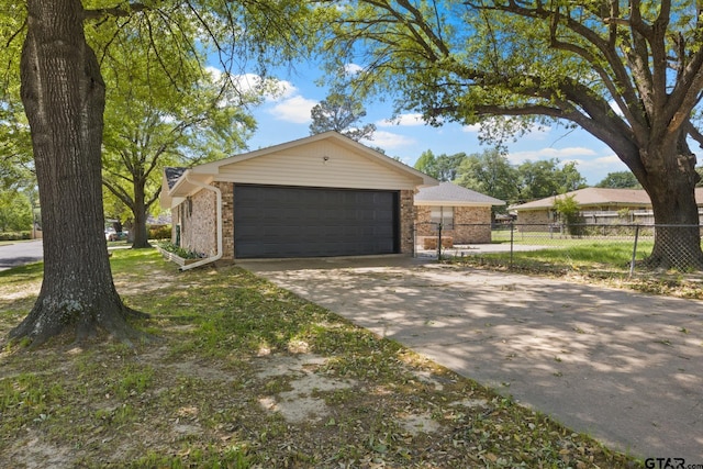 exterior space with concrete driveway, brick siding, and fence