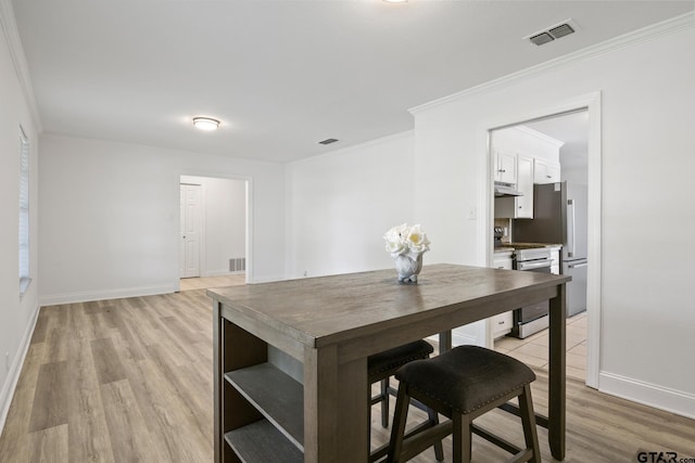 dining room with ornamental molding, visible vents, baseboards, and light wood-style floors